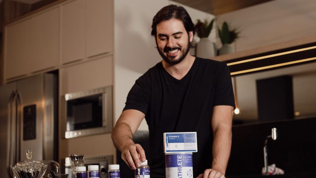 Smiling man arranging vitamin supplements on kitchen counter.