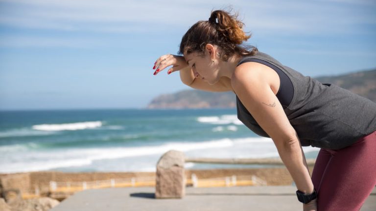 A woman rests after exercise, overlooking the ocean in Portugal's scenic seascape.